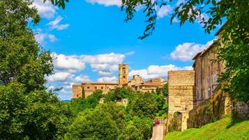A historic stone building with a tower, surrounded by lush greenery and a clear sky.