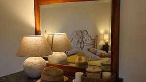 A room with a bed, two lamps, a mirror, and a table with decorative items.