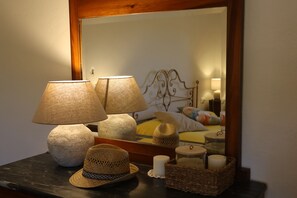 Una habitación con una cama, dos lámparas, un espejo y una mesa con adornos.