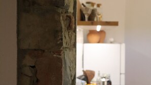 A kitchen with a brick wall, a yellow kettle, and a white refrigerator.