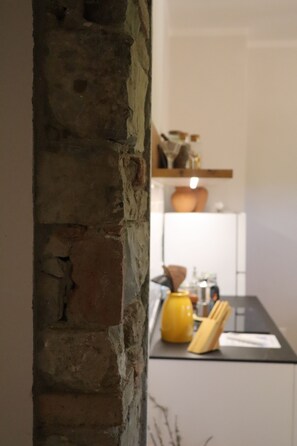 Une cuisine avec un mur en briques, une bouilloire jaune et un réfrigérateur blanc.