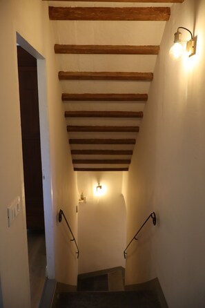 Un escalier avec des poutres en bois, des appliques murales et une main courante.