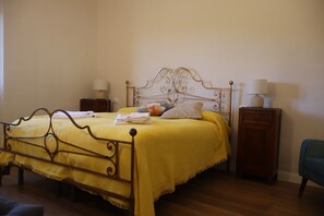 Un lit avec un cadre en métal, une couvre-lit jaune et des oreillers. Il y a deux tables de chevet avec des lampes.