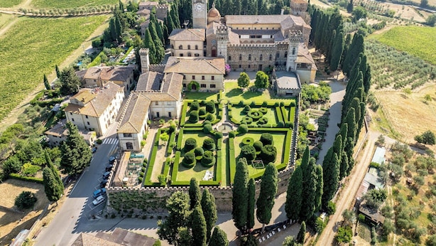 An aerial view of a historic estate with a central courtyard, surrounding buildings, and vineyards.