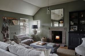 A cozy living room with a fireplace, a sofa, a coffee table, and a bookshelf. - Escape to a luxury 2 bdrm country cottage and ocean views (Kirkcaldy)
