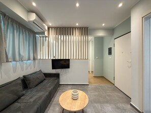 A modern living room with a sofa, a coffee table, a flat-screen TV, and a sliding door leading to another room. - SmartLiving Central Apt 2 (Thessaloniki)