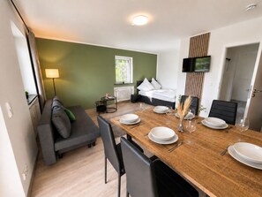 Ett modernt hotellrum med en matplats, en soffa, en säng, en TV och ett fönster.