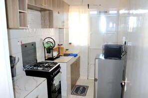 Eine kompakte Küche mit Gasherd, Kühlschrank und Mikrowelle.