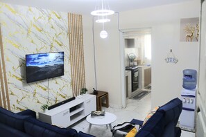 Ein modernes Wohnzimmer mit Fernseher, Wasserspender und einer Couch.