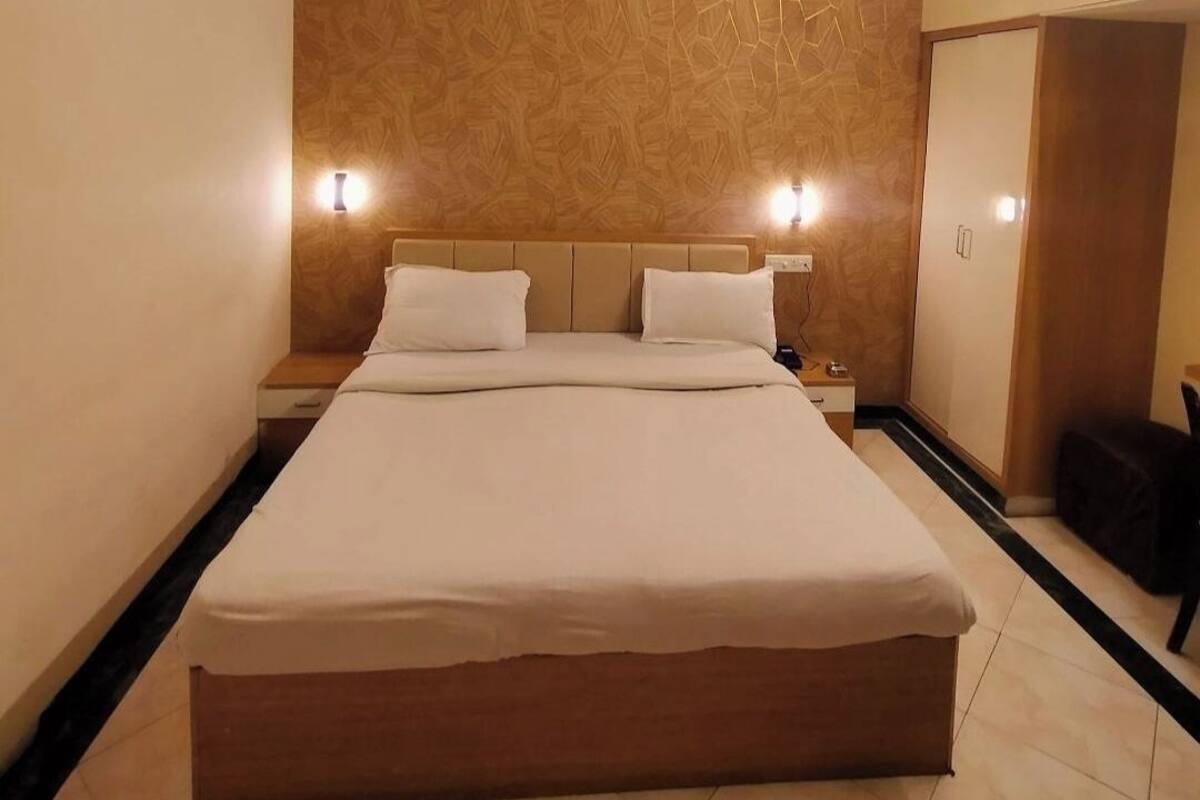 A hotel room with a bed, nightstands, a ceiling fan, and a mirror.