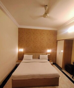 A hotel room with a bed, nightstands, a ceiling fan, and a mirror. - Hotel New Vivaantaa  (Chhatrapati Sambhajinagar)