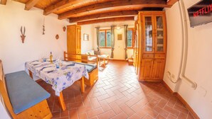 Un comedor de madera con una mesa dispuesta para cuatro, un banco y una zona de cocina con armarios de madera.