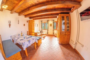 Un coin repas en bois avec une table dressée pour quatre personnes, un banc et un espace cuisine doté de meubles en bois.