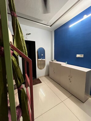 A room with a blue accent wall, a white cabinet, a mirror, and a green chair. - Renee Mysaa (Indore)
