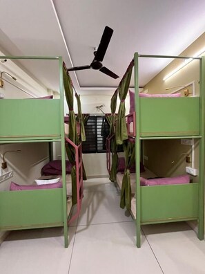 A room with bunk beds, a ceiling fan, and a window with blinds. - Renee Mysaa (Indore)