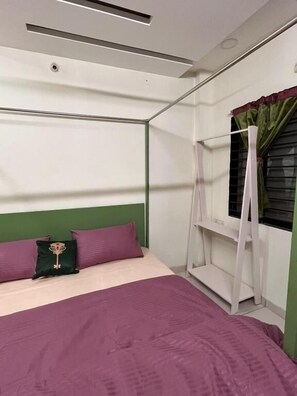 A bed with a green headboard, a window with a curtain, and a white shelf unit. - Renee Mysaa (Indore)