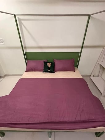 A bed with a green headboard, a purple bedspread, and two pillows.. Renee Mysaa