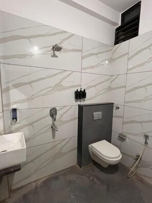 A bathroom with a toilet, sink, and shower. - Renee Mysaa (Indore)