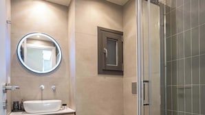 A modern bathroom with a glass shower enclosure, a round mirror, and a wooden vanity. - Modern Studio l Huge Balcony l New Bldg (Athens)