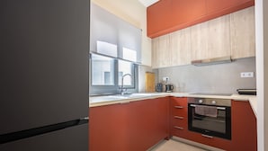 A kitchen with a refrigerator, oven, sink, and wooden cabinets. - Modern Studio l Huge Balcony l New Bldg (Athens)