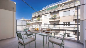 A balcony with a table set for breakfast, chairs, and a view of a multi-story building. - Modern Studio l Huge Balcony l New Bldg (Athens)