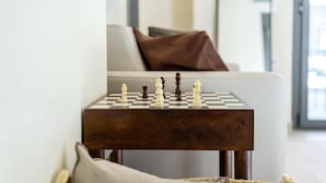 A chessboard on a wooden table in a modern living room with a sofa and cushions in the background. - Modern Studio l Huge Balcony l New Bldg (Athens)