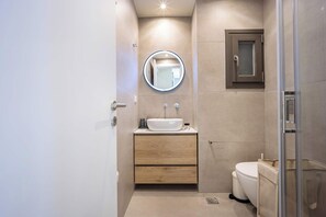A modern bathroom with a sink, mirror, and toilet. - Modern Studio l Huge Balcony l New Bldg (Athens)