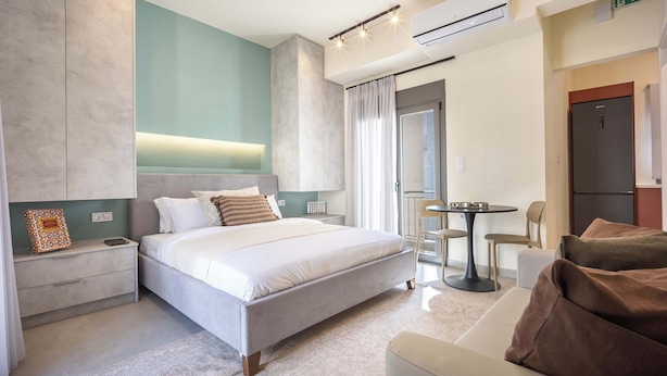A modern hotel room with a large bed, bedside tables, a small round table, a sofa, and a view of the outside. - Modern Studio l Huge Balcony l New Bldg (Athens)
