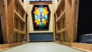 Een kamer met een houten balkenplafond, een centraal geplaatst mozaïekraam en een vloer van tatami matten.