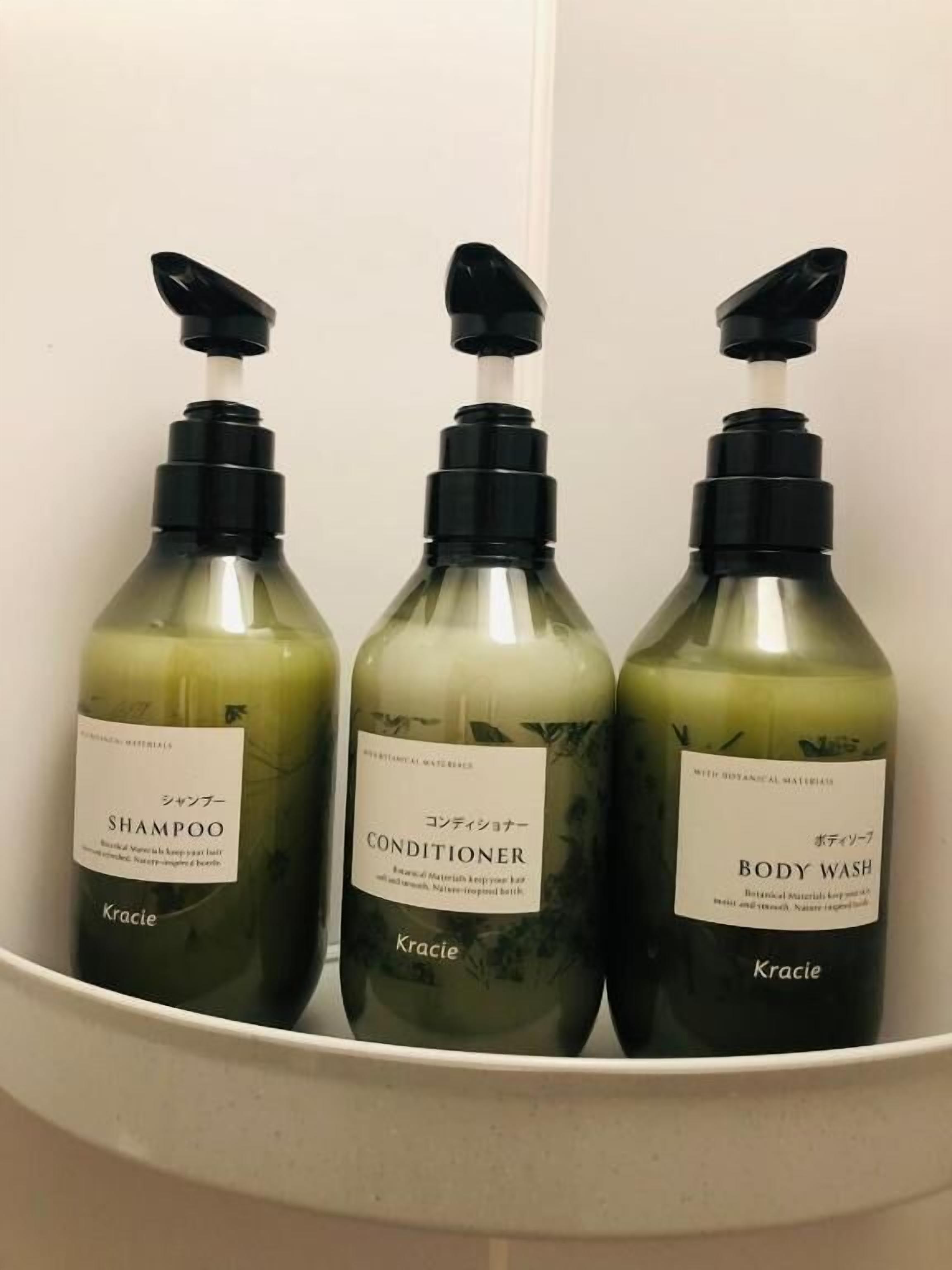 Three bottles of Kracie body wash, conditioner, and shampoo in a white container.