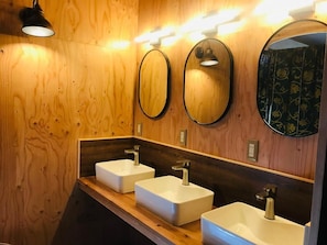 A wooden wall with three white sinks and overhead lighting. - Guesthouse Mitaki (Hiroshima mitaki honmachi)
