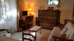A cozy living room with a fireplace, a television, and a table with a patterned tablecloth. - Mornac-sur-Seudre, house in the heart of the village (Mornac-sur-Seudre)