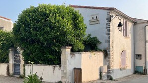 Un edificio con un muro de piedra, un portón de madera y un gran árbol.