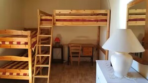 Habitación con literas, un escritorio, una silla, una lámpara y una escalera.
