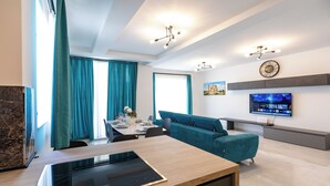 Een moderne woonkamer met een bank, een flatscreen-tv en een eethoek met een tafel gedekt voor twee personen.