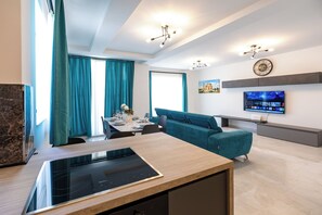 A modern living room with a sofa, a flat-screen TV, and a dining area with a table set for two. - Enjoy a bright 3-bedroom, 2-bathroom apartment on the 4th floor with lift access in St Paul’s Bay. Featuring a spacious living area, modern kitchen, balcony/terrace, sea views, and air conditioning, it is ideal for families and groups. (St. Paul's Bay)