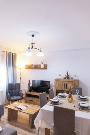 A dining area with a table set for four, a television, and a wooden cabinet. - Vrbo Property (Torrijos)