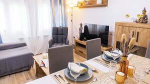 A modern living room with a sofa, chairs, a TV, and a dining area with a table set for two. - LODGING IN TORRIJOS TOLEDO ALOJAMIENTO TURISTICO DON PEDRO TOLEDO (Torrijos)