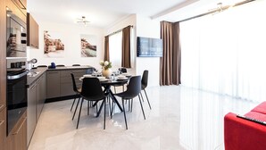 Une cuisine moderne avec un coin repas, un canapé rouge et un téléviseur fixé au mur.