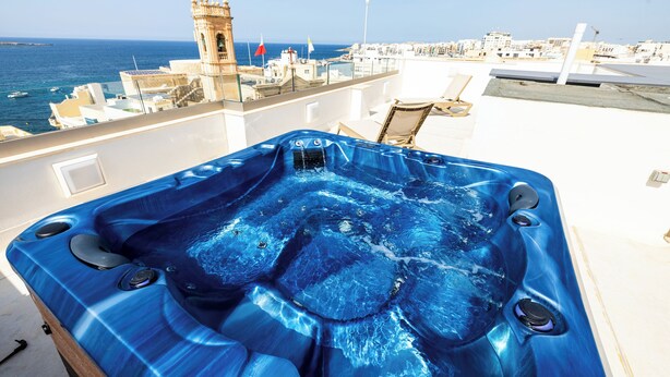 Un jacuzzi sur un toit, avec vue sur la mer et les bâtiments.