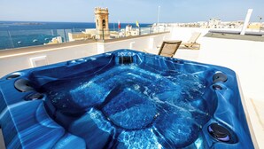 Un jacuzzi avec jets massants, une vue sur la mer et un paysage urbain en arrière-plan.