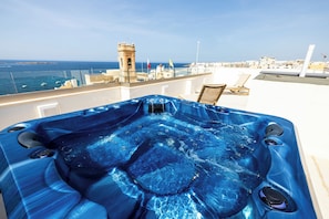 Ein Whirlpool mit Düsen, Blick auf das Meer und eine Stadtlandschaft im Hintergrund.
