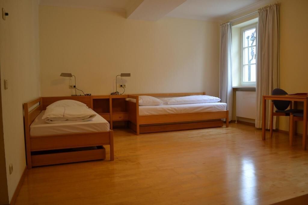 Una habitaci ón con dos camas de madera, un escritorio y una silla.