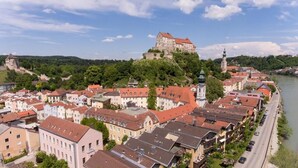 A historic town with a prominent castle on a hill, narrow streets, and a river. - Haus der Begegnung HEILIG GEIST (Burghausen)