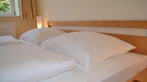 A bed with white bedding and a wooden headboard. - Haus der Begegnung HEILIG GEIST (Burghausen)