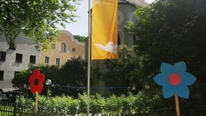 A building with a dome, a yellow flag, and a blue flower-shaped sign. - Haus der Begegnung HEILIG GEIST (Burghausen)