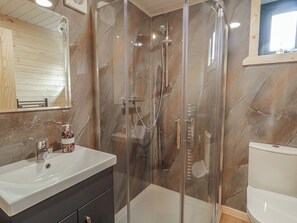 A bathroom with a glass-enclosed shower, a white sink, and a toilet. - Alken The Stag (Bushmills)