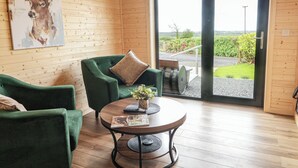 Un interior de madera con un sofá verde, una mesa con revistas y un cuadro de un ciervo.