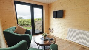 Una habitación acogedora con un sofá verde, una mesita con una planta y un televisor montado en la pared.