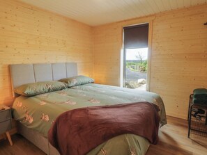 A bedroom with a bed, a nightstand, a chair, and a window with a view of the outdoors. - Alken The Stag (Bushmills)